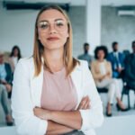 Shot of confident business leader standing in a board room with crossed arms and looking at camera. Businesswoman leading a training class for professionals.