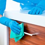Close up of woman's arms cleaning and polishing kitchen cabinets.